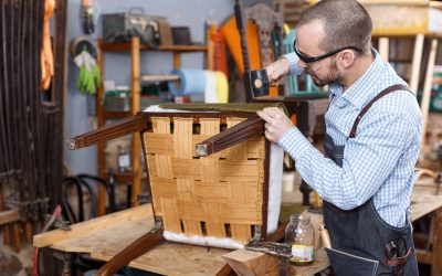 Craftsman reupholstering chair in workshop Qualified workman upholstering chair in repair furniture workshop